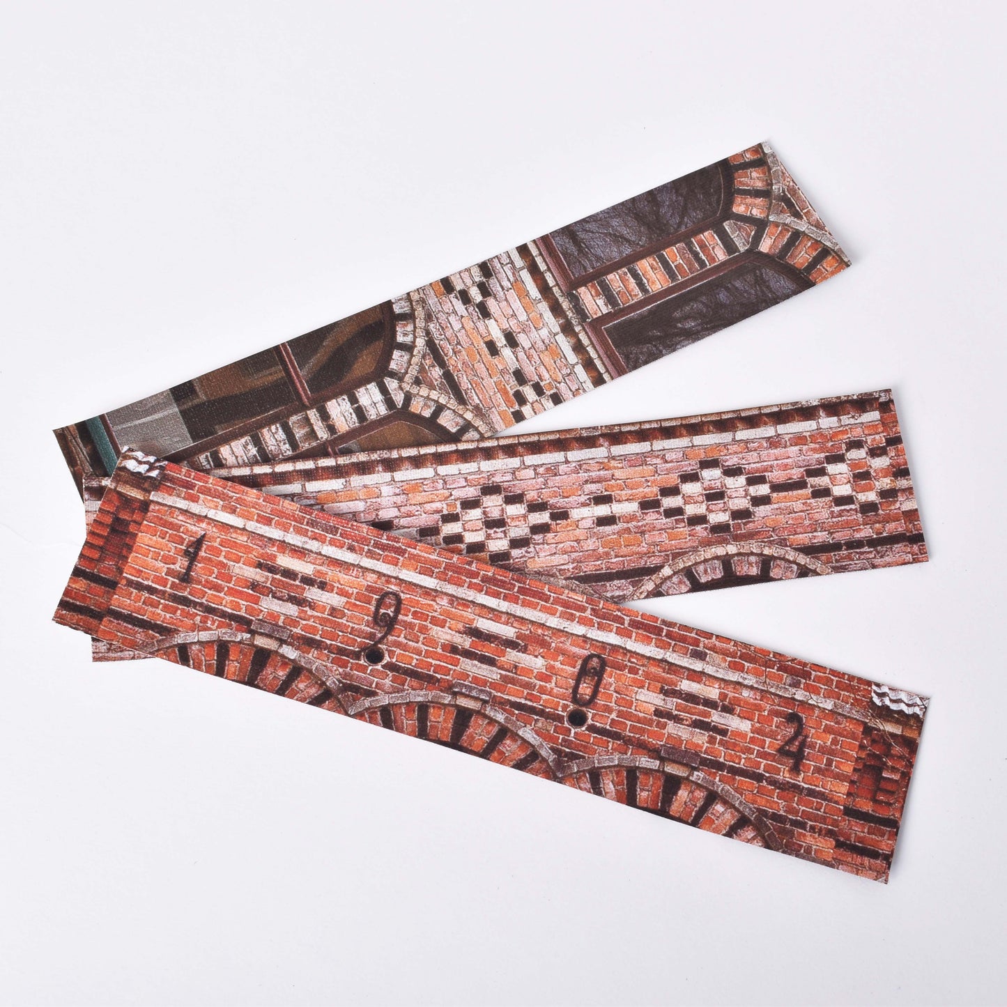 Tre bokmärken i tyg med olika motiv från tegelfasaden på Gustavsbergs Porslinsmuseum