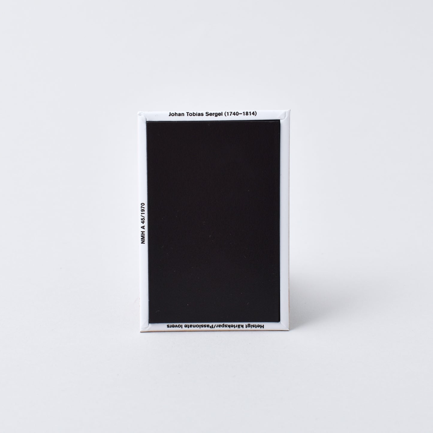 baksida av rektangulär magnet med konstnärens namn och titel på verket