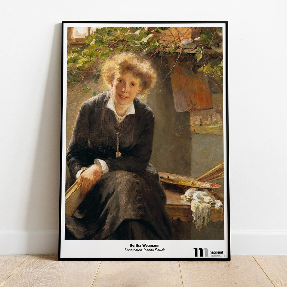 Poster med Jeanna Baucks porträtt av Bertha Wegmann i svart ram mot en vägg