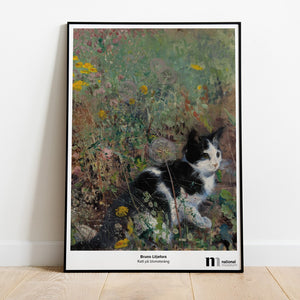 Poster med katt på blomsteräng i svart ram lutad mot en vägg